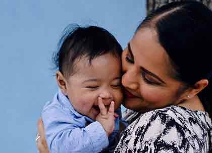 A photo of a Latina mom happily holding her baby