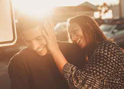  A photo of a woman leaning her left hand against a man’s face, both smiling