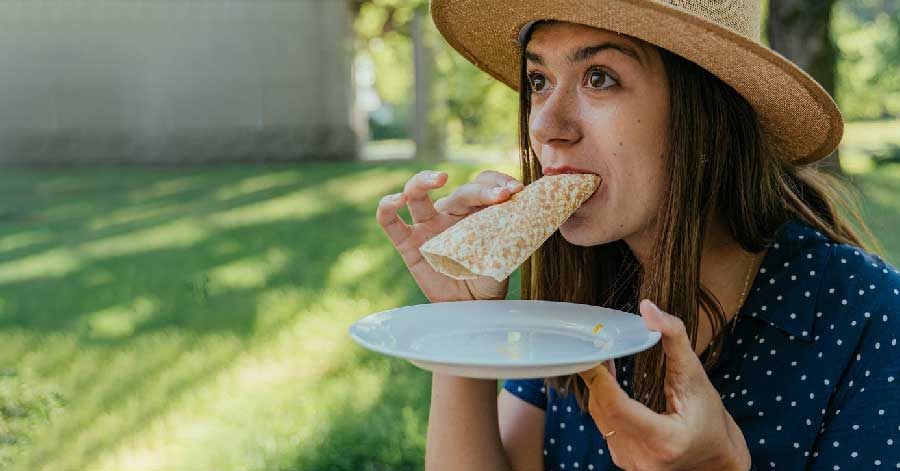 woman eating a folded flatbread